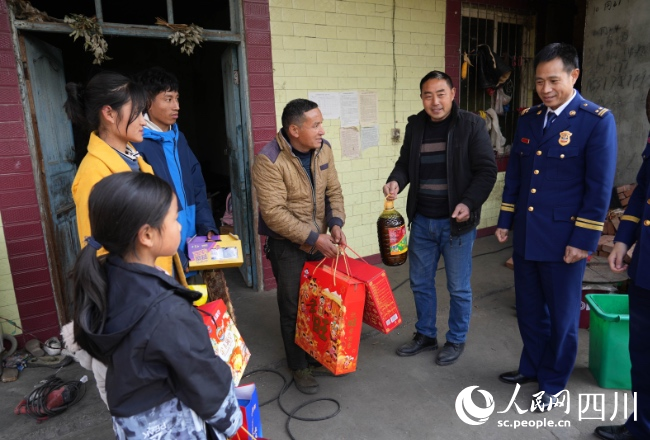 1月17日，在雅安市石棉縣王崗坪彝族藏族鄉愛國村，消防救援人員為正在看望慰問肖華平一家。李從林攝