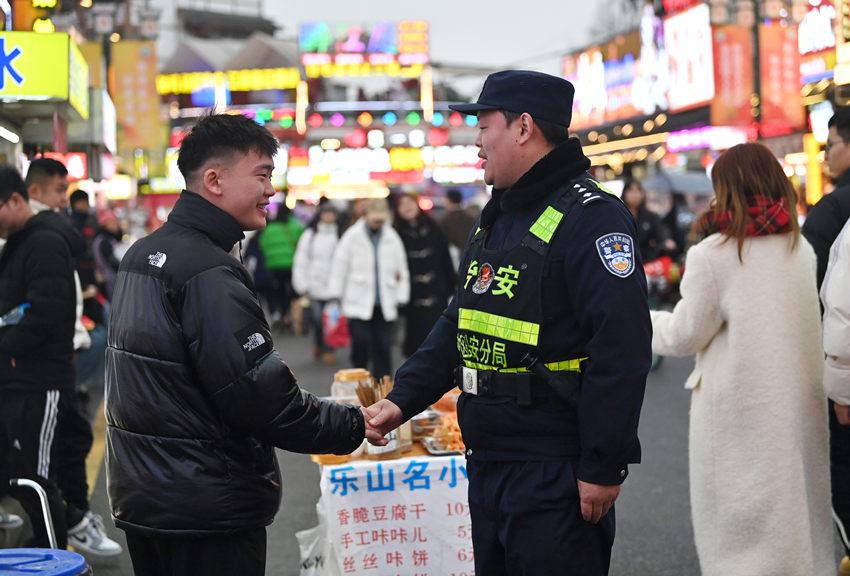 被幫助的游客和樂山市公安局市中區(qū)分局張公橋派出所副所長白科翔握手，表示感謝。樂山公安供圖