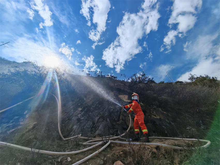 眉山市消防救援支隊救援人員利用40水帶出槍，對雅江縣降央寺周邊植被進行澆灌、降溫冷卻。四川省消防救援總隊供圖