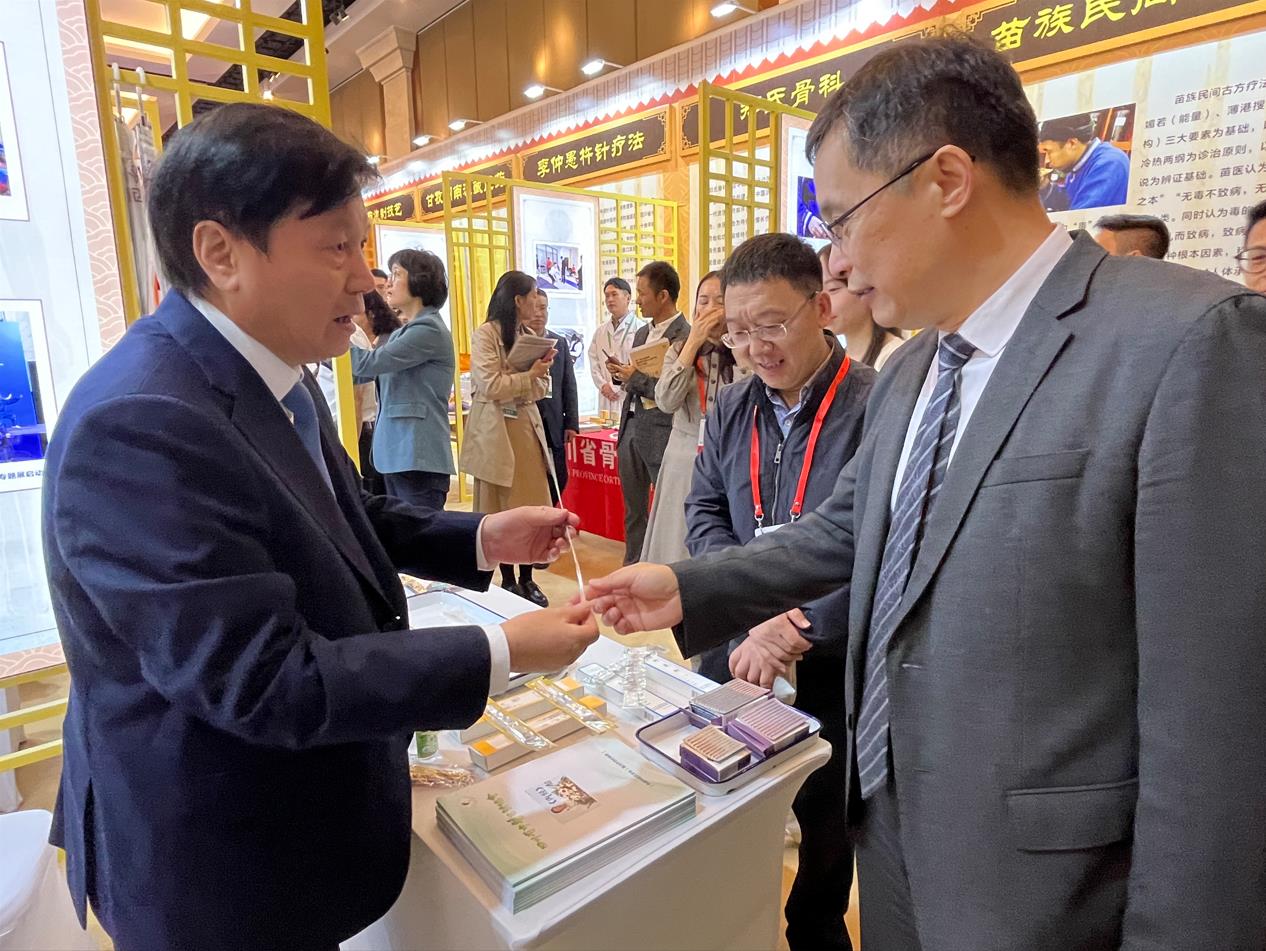 中醫藥展覽展示大會上，唐德厚（左）向國家中醫藥管理局副局長黃璐琦（右）介紹“唐氏芒針”。受訪者供圖