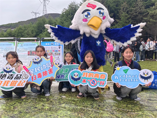 當地學生和涼山禁毒IP“火洛”合影。美姑縣委禁毒辦供圖