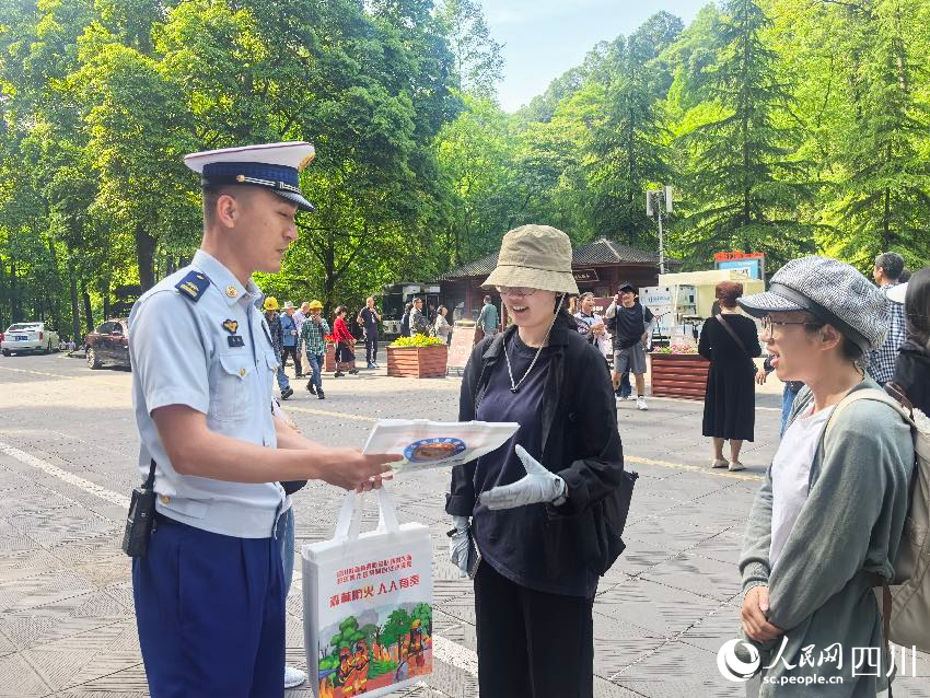 5月1日，青城山門口，消防員裴樂向游客發(fā)放防火宣傳單，普及森林防火常識(shí)。程雪力攝