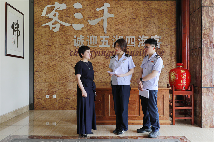 成都稅務工作人員向客三千酒廠財務負責人講解“銀稅互動”政策，送上《支持制造業(yè)發(fā)展主要稅費優(yōu)惠政策指引》。成都市稅務局供圖