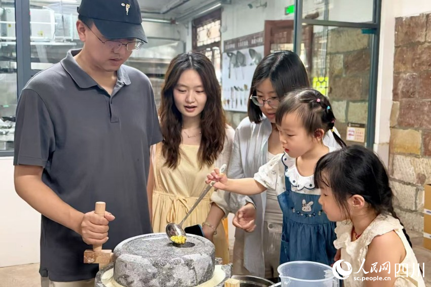參加研學的孩子在家長的陪同下，上手體驗先市醬油制作（部分環節）。楊藺攝